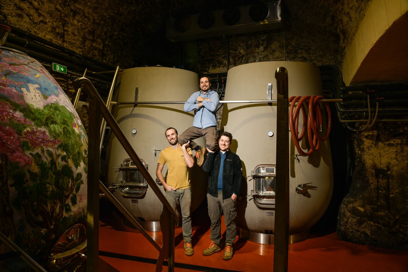 Arthur, Hugo and Jean in the vaulted cellar, between two large concrete vats, beside a painted vat